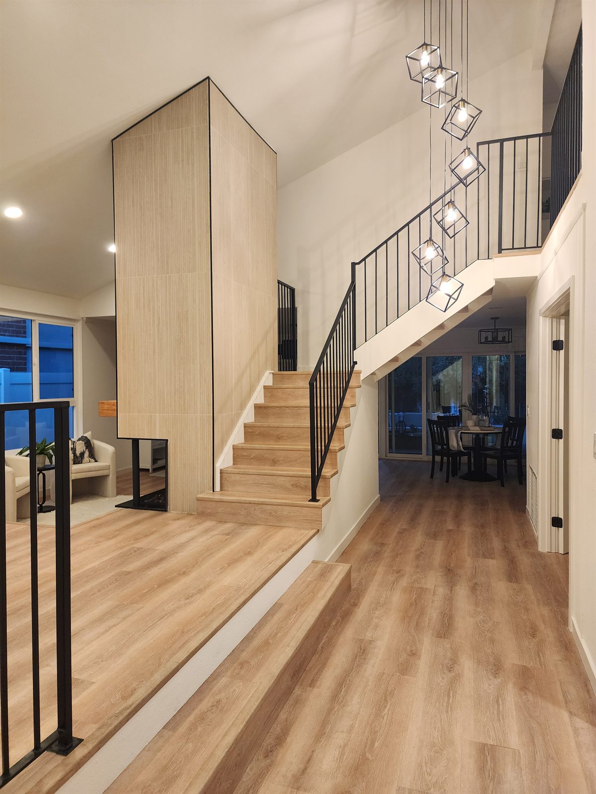 Staged entry and staircase in a Tustin home by Staging OC — light wood treads, black metal railing, and a cube pendant cluster in a double-height entry